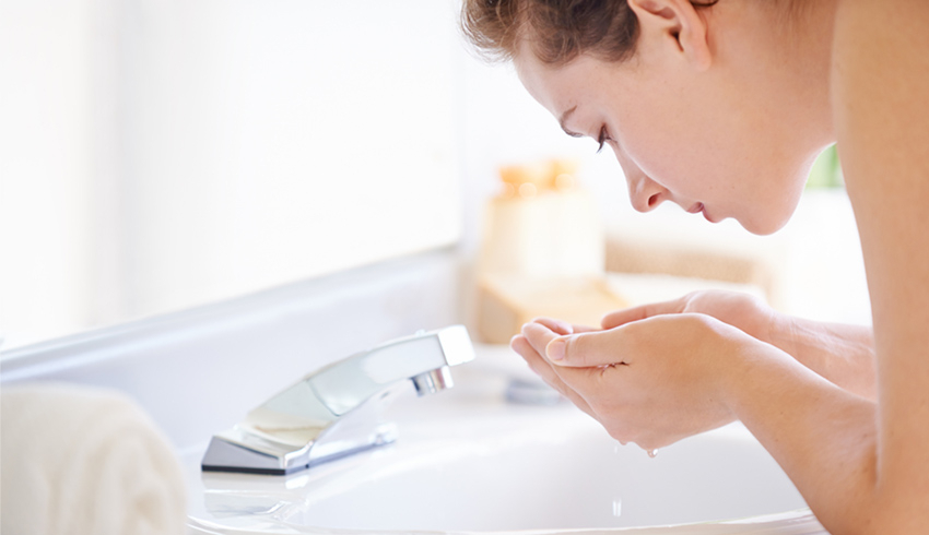 Woman washing face at sink